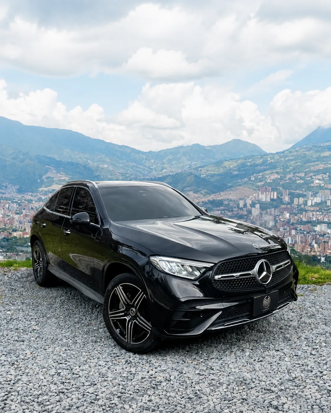 Mercedes-Benz GLC 300 negra con rines bicolor, de tres cuartos frontal, sobre un mirador con Medellín al fondo.