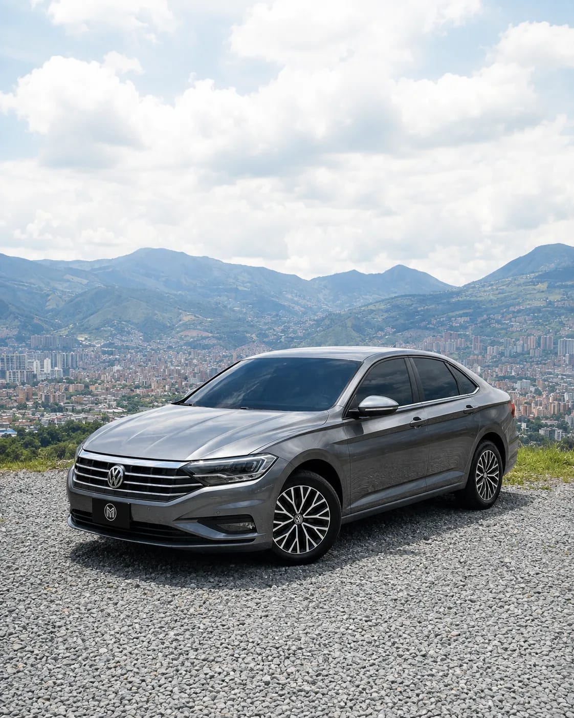 Volkswagen Jetta gris de tres cuartos frontal, sobre un mirador con Medellín al fondo.